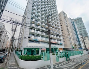 Un edificio de varios pisos con balcones, una entrada a nivel de calle y un cartel que indica que es un hotel.
