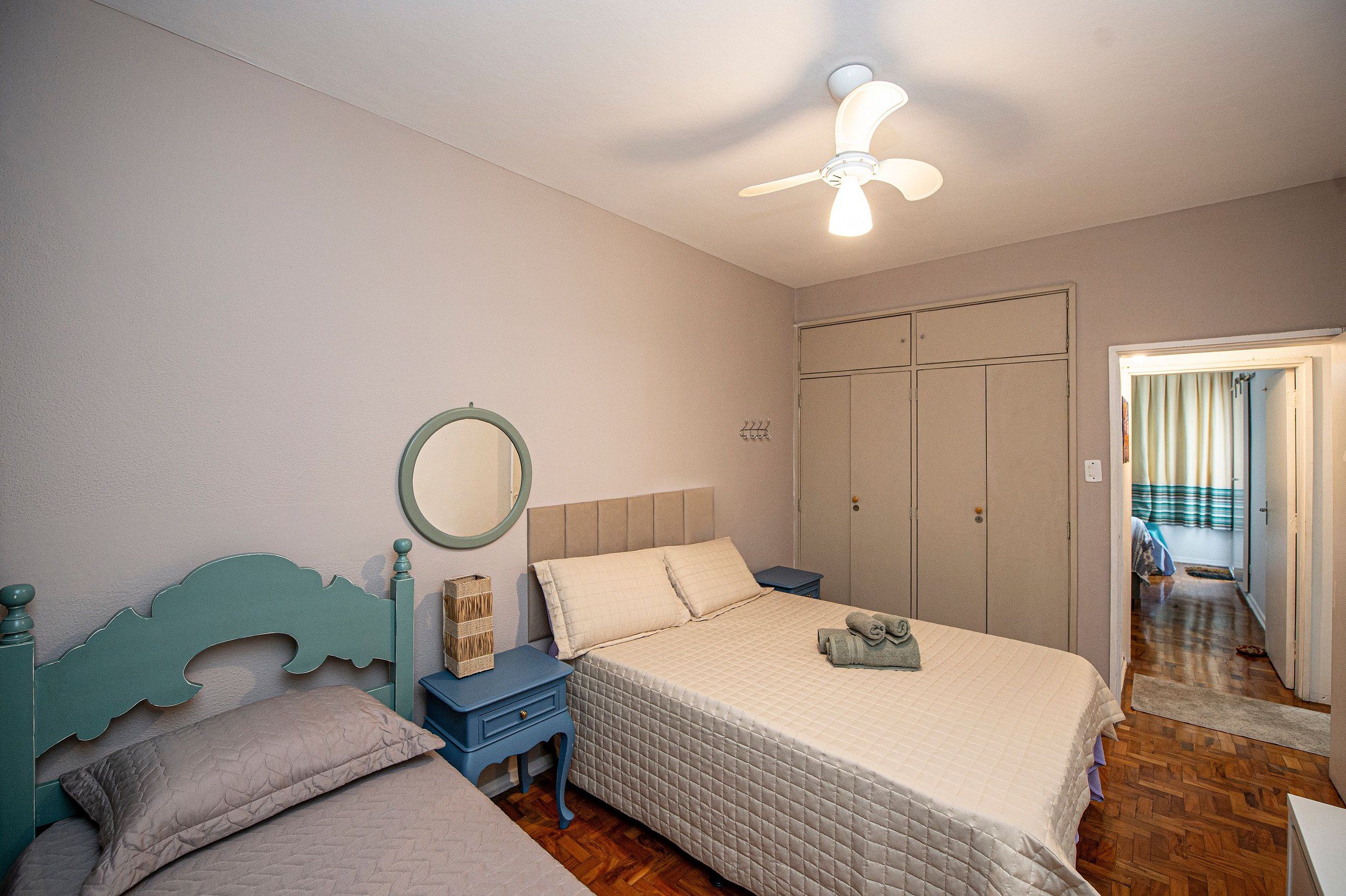 A bedroom with a bed, a nightstand, a dresser, a mirror, and a ceiling fan.
