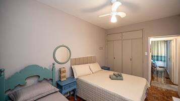 A bedroom with a bed, a nightstand, a dresser, a mirror, and a ceiling fan.