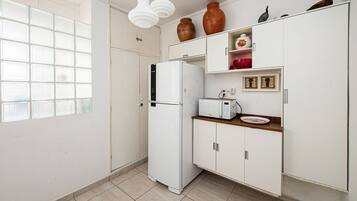 Una cocina compacta con un refrigerador blanco, un microondas y una encimera de madera.