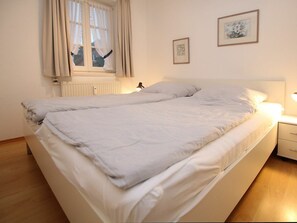 A double bed with white bedding, a bedside table with a lamp, and two framed pictures on the wall. - 1, Dorpstraat 9 (Wyk auf Foehr)