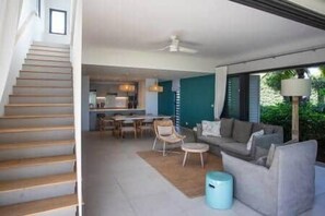 Ein modernes Interieur mit einer Treppe, einem Essbereich und einem Wohnraum mit einer Couch und einer Lampe.