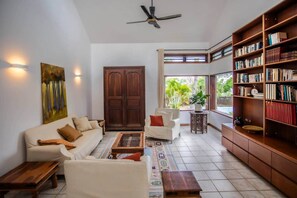 A living room with a sofa, armchairs, a coffee table, a bookshelf, and a large wooden door. - The Villa - Le Morne (Le Morne)