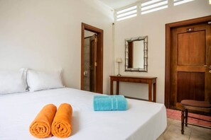 A hotel room with a bed, a wooden desk, a mirror, and a door. - The Villa - Le Morne (Le Morne)