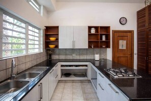 Een keuken met een gasfornuis, een spoelbak en een raam.