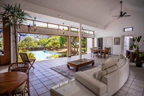 Uma sala de estar ampla com piscina, conjunto de jantar e sofá.