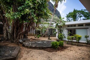 A courtyard with a stone pathway, a palm tree, and a building with a white facade. - The Villa - Le Morne (Le Morne)