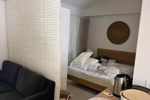 Ein Hotelzimmer mit einem Bett, einem Nachttisch mit Wasserkocher, einer Lampe und einem runden Spiegel an der Wand.