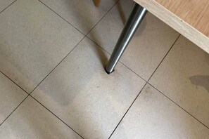 Un piso de baldosas con un pata de metal de un mueble.