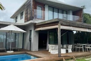 A modern two-story house with a pool, outdoor seating, and a covered patio area. - Beachfront Luxury Villa & pool (Black River)