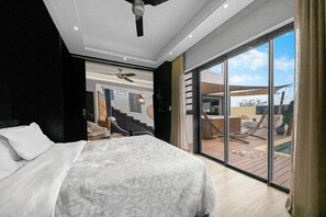 Ein Schlafzimmer mit einem großen Bett, einem Deckenventilator und Blick auf eine Terrasse mit einem Pool.