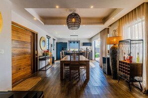 Cozinha moderna com área de jantar, piso de madeira e luminária pendente.