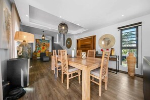 Ein moderner Essbereich mit einem Holztisch und Stühlen, einer großen Vase und einer außergewöhnlichen Deckenleuchte.