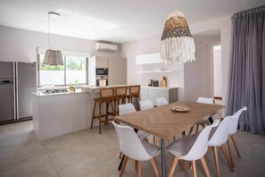 A modern kitchen with a central island, white chairs, and a dining table. - Luxury Tropical Villa - Pool and Close to Beach (Tamarin)