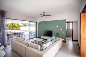 Ein modernes Wohnzimmer mit einer Couch, einem Fernseher und einem Essbereich mit Stühlen und einem Tisch.