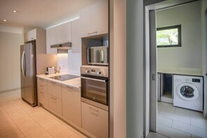 A modern kitchen with stainless steel appliances, a built-in oven, and a microwave. - Beachfront Villa with Private Pool (Black River)