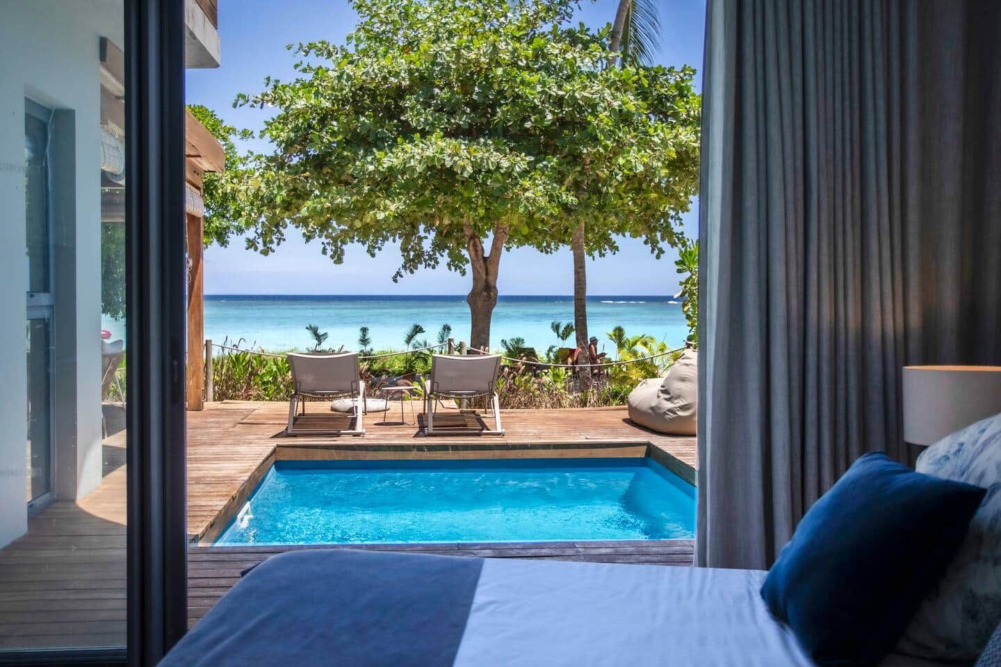 A bedroom with a view of a swimming pool and the ocean.