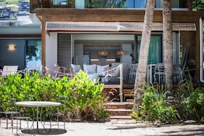A modern building with a covered outdoor seating area, a staircase leading to the entrance, and lush greenery. - Beachfront Villa with Private Pool (Black River)