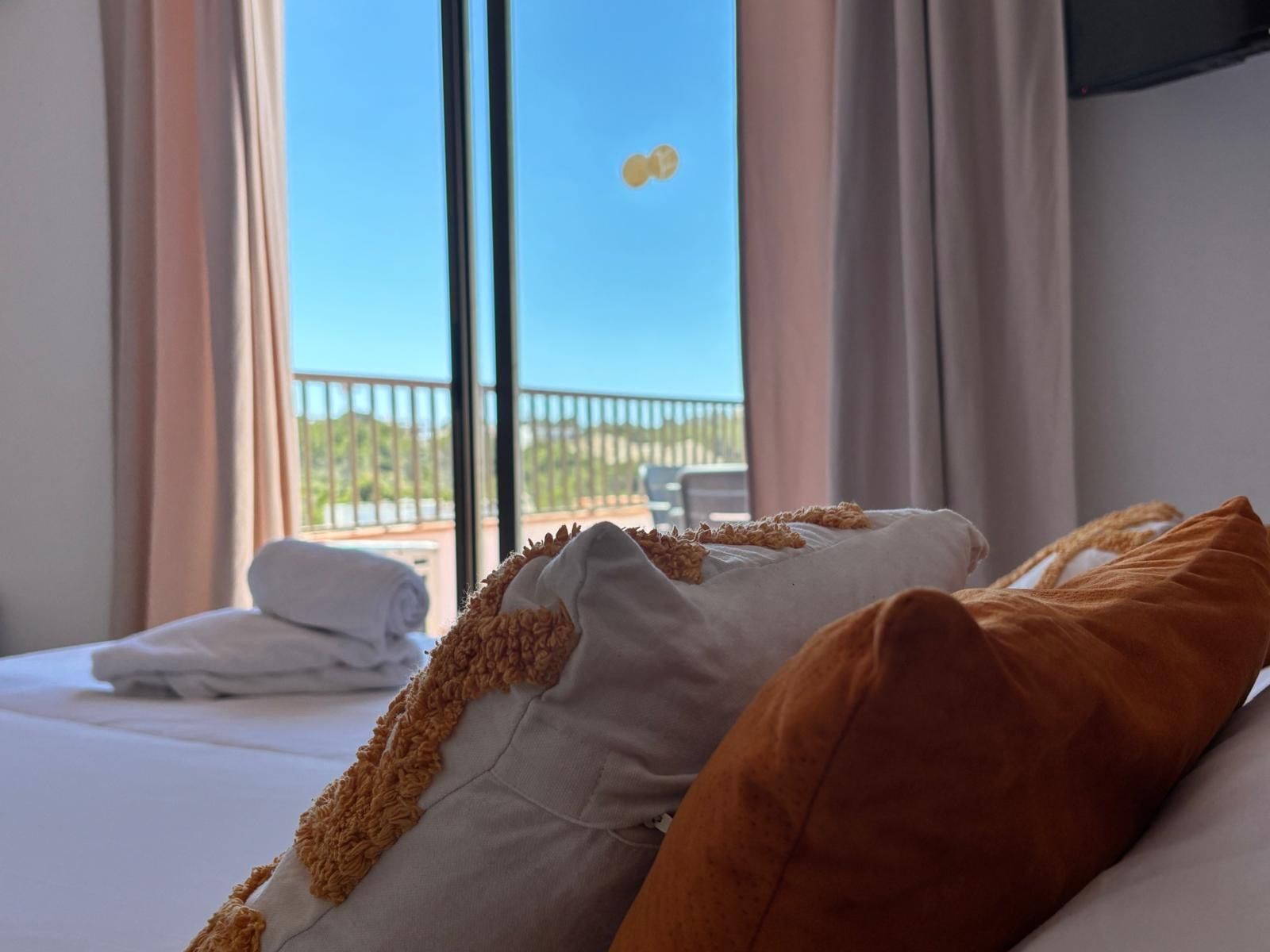 Una habitación de hotel con cama, vista a un balcón y una ventana.