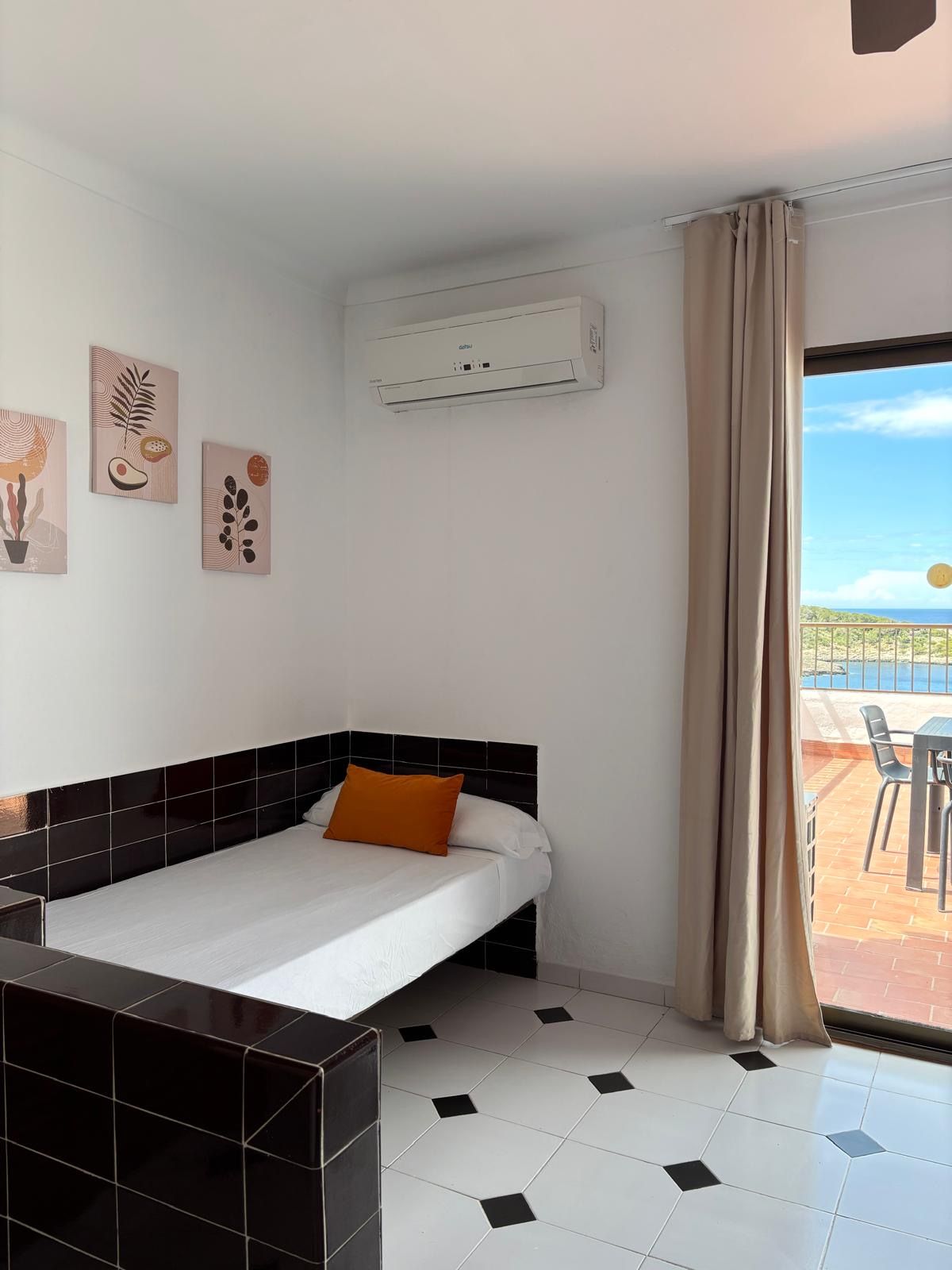 Une chambre d’hôtel avec un lit, une petite table, une chaise et une vue sur la mer.