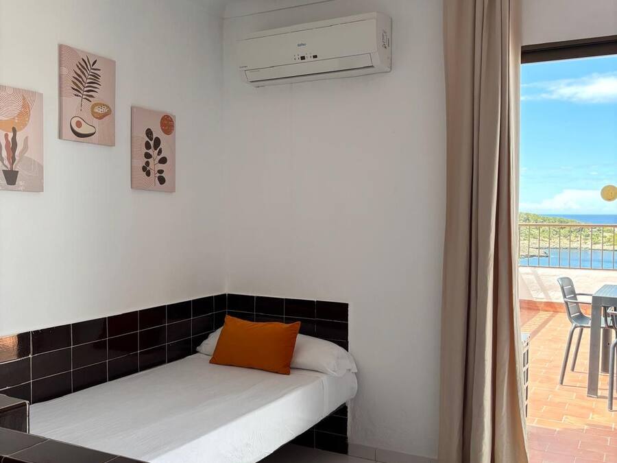 Une chambre d’hôtel avec un lit, une petite table, une chaise et une vue sur la mer.