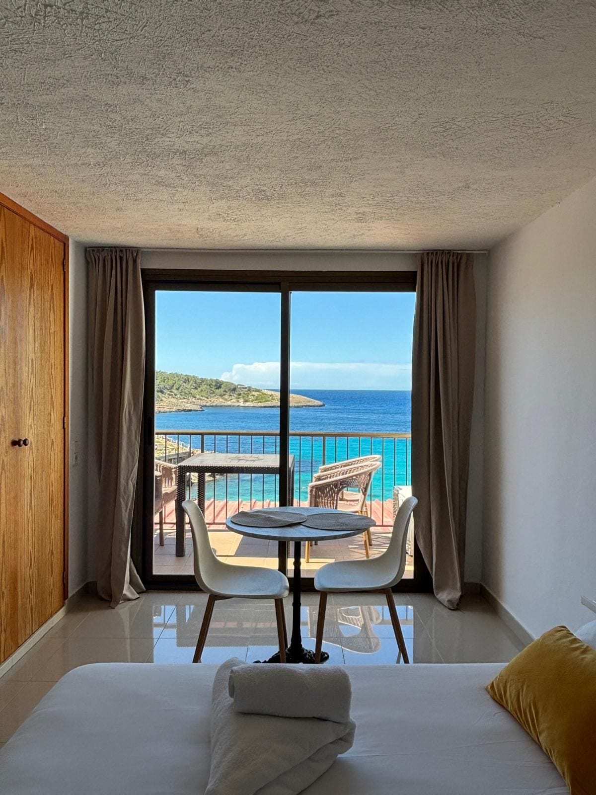 Habitación de hotel con balcón, cama y vista al mar.