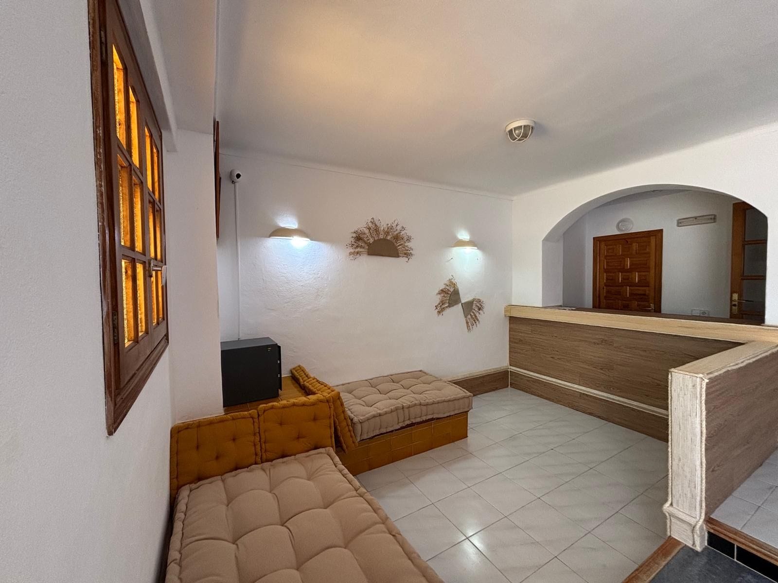Ein Zimmer mit einem Bett, einem kleinen Tisch und einer Wandleuchte.