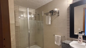 A bathroom with a glass-enclosed shower, a toilet, a sink with a granite countertop, and a mirror. - es grop apartamentos (Portinatx)