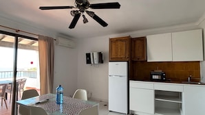 A compact kitchen with white cabinets, a built-in microwave, and a small refrigerator. - es grop apartamentos (Portinatx)