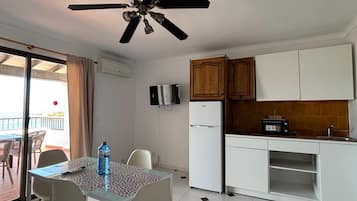 A compact kitchen with white cabinets, a built-in microwave, and a small refrigerator.