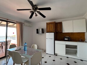 Une cuisine compacte avec des meubles blancs, un four à micro-ondes encastré et un petit réfrigérateur.
