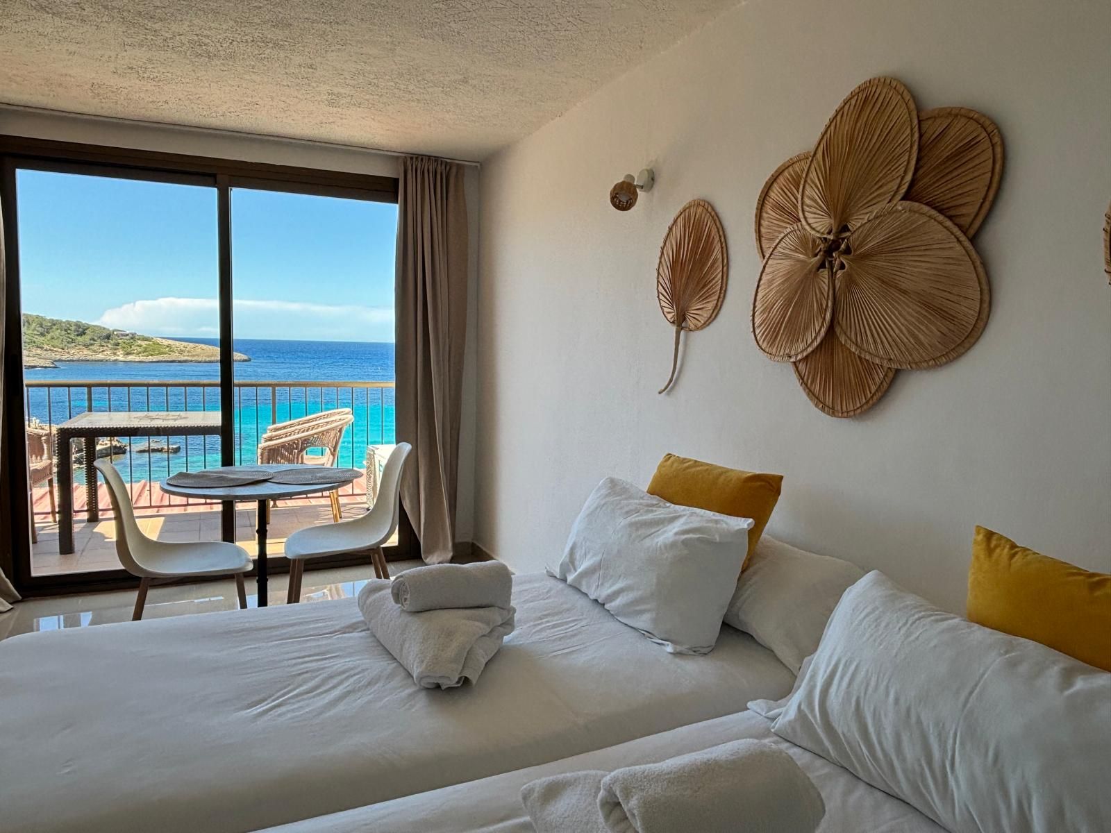 Une chambre d’hôtel avec balcon, un lit avec du linge de maison blanc et une vue sur la mer.