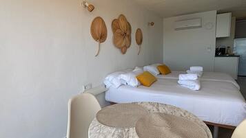 A hotel room with a bed, two pillows, a round table with a placemat, a chair, and wall-mounted wall art.