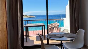 Ein Zimmer mit Meerblick, ein Balkon mit Tisch und Stühlen und zwei weiße Stühle im Inneren.