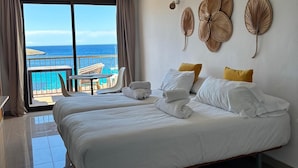 A hotel room with a bed, a view of the sea, and a balcony with outdoor seating. - es grop apartamentos (Portinatx)