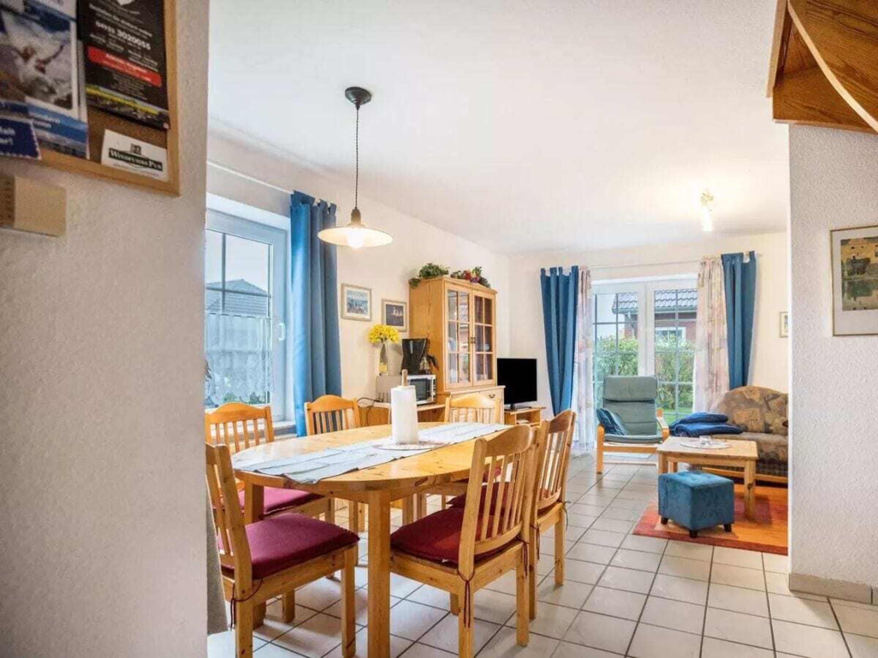 Ein Essbereich mit einem Holztisch, Stühlen, einem Schrank und einem Fernseher.