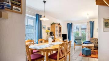Un coin repas avec une table et des chaises en bois, un buffet et un téléviseur.
