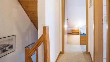 A narrow hallway leading to a bedroom with a bed and a nightstand.