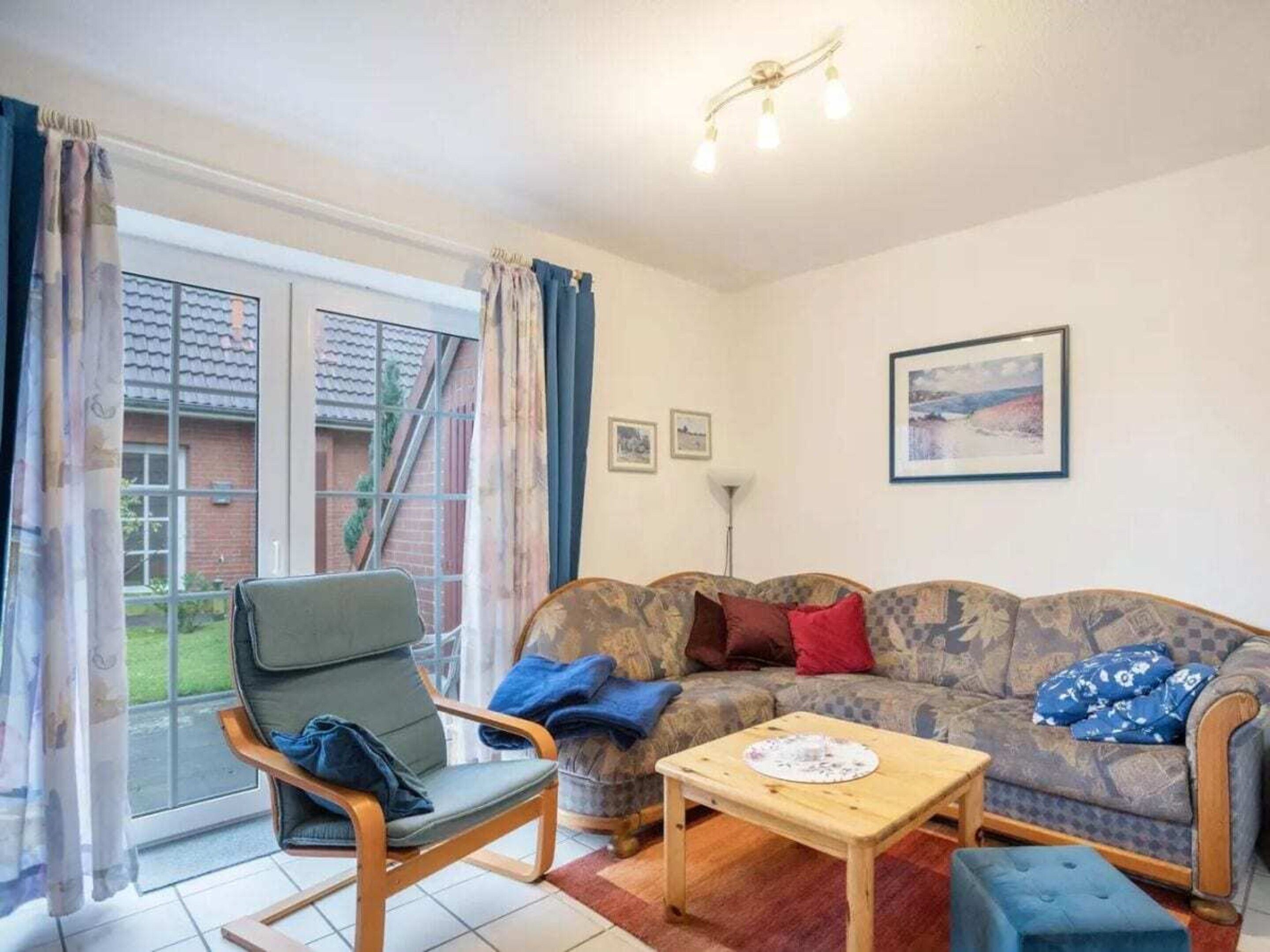 A living room with a sofa, a chair, a table, and a window with curtains.