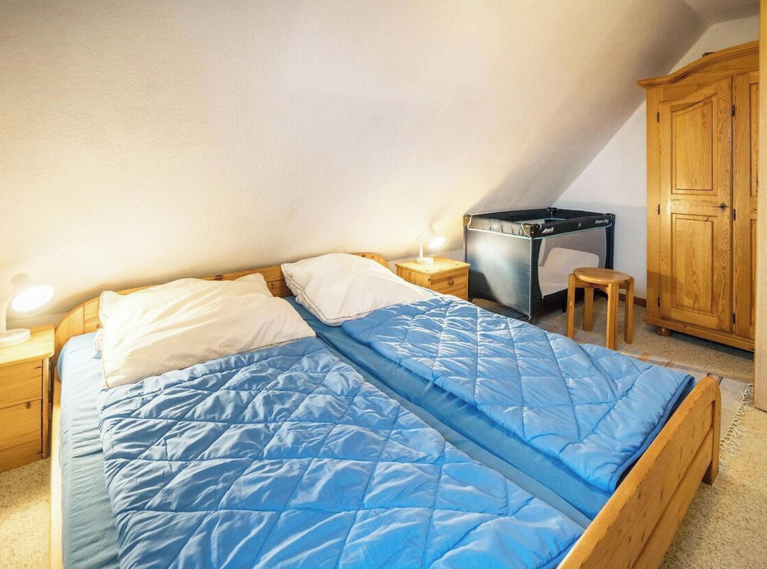 A bedroom with a bed, a nightstand, a small stool, a cabinet, and a suitcase.