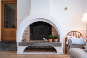 A fireplace with a white mantel, two potted plants, and a 'Relax' sign.