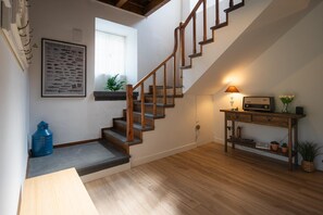 A staircase with wooden steps and a handrail, a small table with a lamp, and a wall-mounted picture frame.