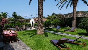A well-maintained outdoor patio with a dining table, chairs, and lounge chairs. - Vrbo Property (Rabo de Peixe)
