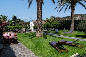 Une terrasse extérieure bien entretenue, avec une table à manger, des chaises et des fauteuils de jardin.