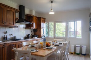 A kitchen with wooden cabinets, a central island with seating, and a view of greenery outside.