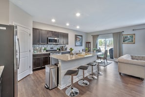 A modern kitchen with a central island, stainless steel appliances, and bar stools.