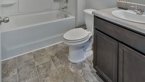 Une salle de bain équipée d’une baignoire, de toilettes, d’un meuble-lavabo et d’un miroir.