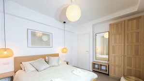 Une chambre d’hôtel avec un lit, des lampes de chevet, un miroir et une armoire.