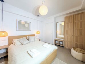 Una habitación de hotel con cama, lámparas de noche, un espejo y un armario.