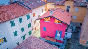 Un edificio residencial de varios pisos con techo rojo, fachada rosa y un balcón con barandilla.